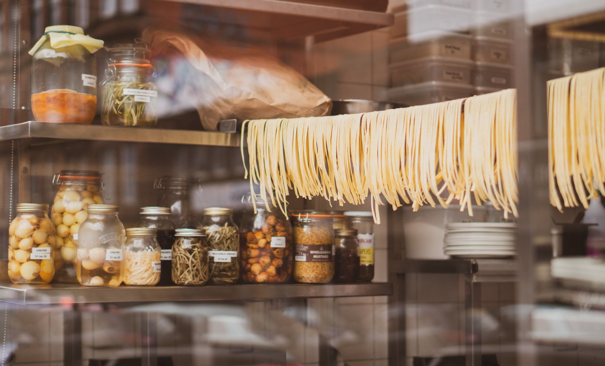 Fersk pasta henger til tørk på ei snor i en butikk